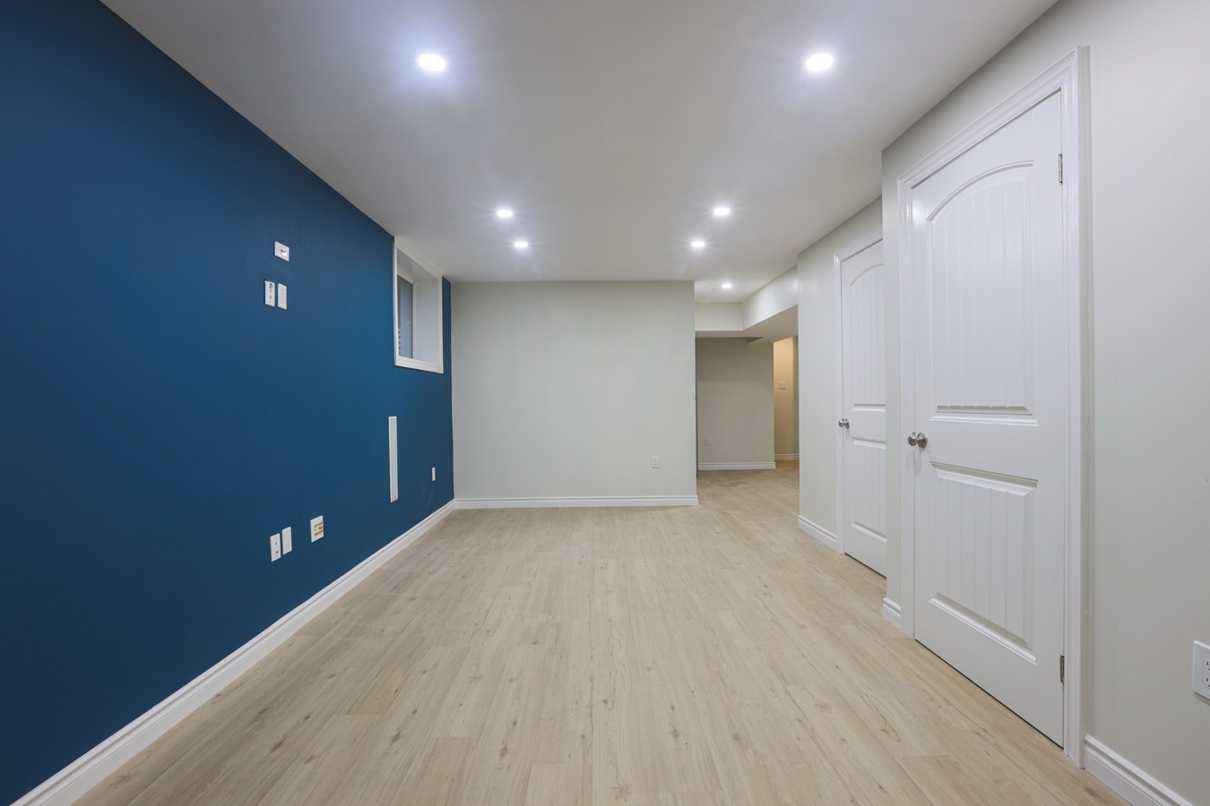 Finished basement with navy feature wall and recessed pot lights